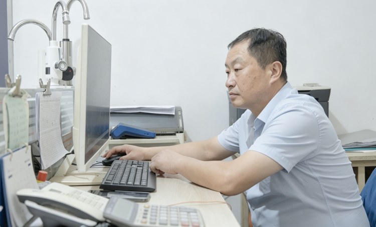 杨军朝在办公室查看市场资料